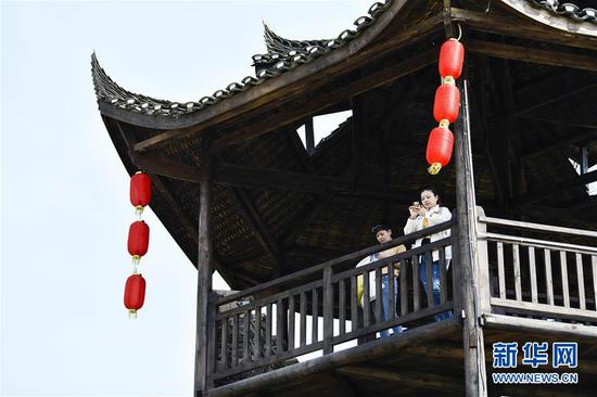  游客在重慶市武隆區(qū)黃鶯鄉(xiāng)復(fù)興村的觀景樓上欣賞田園景色（2019年3月28日攝）。 新華社記者 劉潺 攝